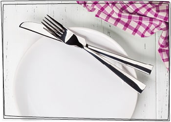 Mangelernährung dargestellt durch einen leeren Teller mit aufliegendem Besteck.